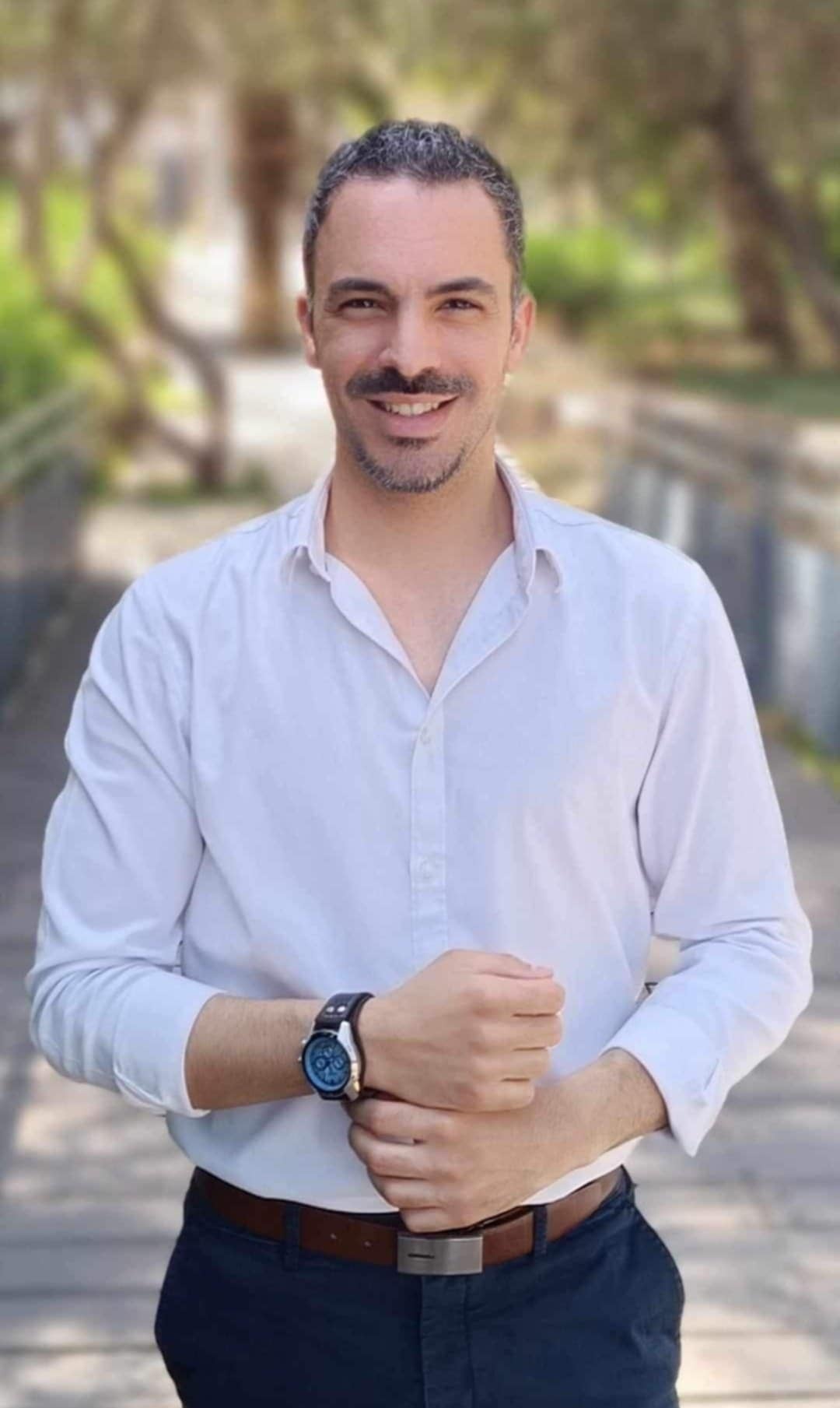 Ο Στέφανος Φλουρέντζου χαμογελαστός, με λευκό πουκάμισο, σε υπαίθριο χώρο με δέντρα
